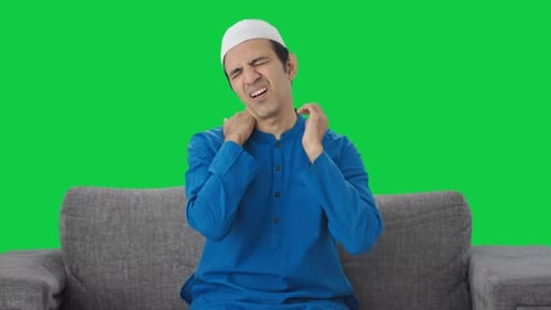 Sick Muslim man suffering neck pain Green screen