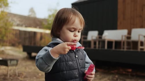 Happy Child Blowing Bubbles Outside at Home