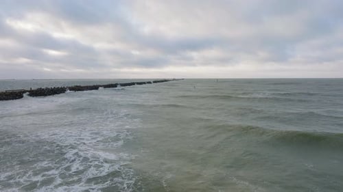 Establishing aerial view of a man engaged in kitesurfing, overcast winter day, high waves, extreme s