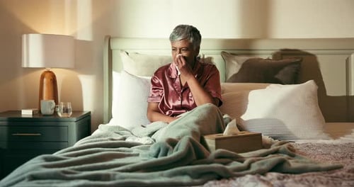 Sick Woman Sits in Bed With Tissues