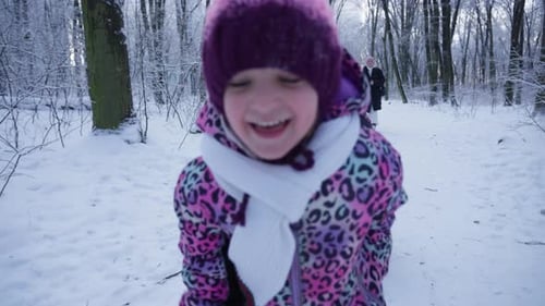 Sister is Sledding Her Brother in a Snowy Winter Forest