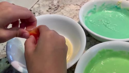 Small hands squeezing food coloring into bowls of colorful pastel colored cake batter. Fun, easy, in