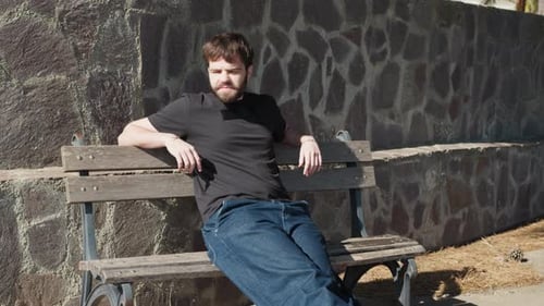 Man Relaxing on Bench in Urban Park