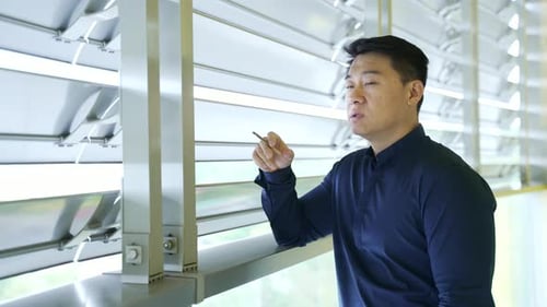 Homme d'affaires asiatique confiant fumant une cigarette pendant une pause au travail, seul, Portrait d'une personne attirante