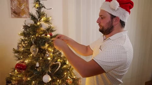 Man in Santa Hat Decorating Christmas Tree