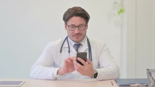 Middle Aged Doctor Using Smartphone in Clinic