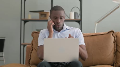 Man Using Laptop While Talking on Cell Phone