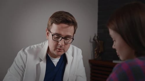 A Male Doctor Consults a Female Patient Scheduled Appointment in a Modern Clinic Communication and