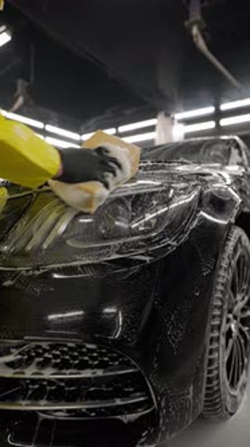 Worker Washes Car with Sponge Detailed Cleaning Process in Modern Car Wash Center