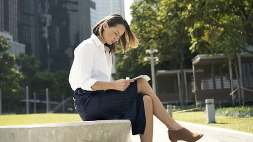 Young Executive Reading News in City Park