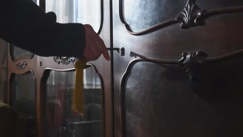 Mysterious figure with key opens wardrobe door in moody suspense