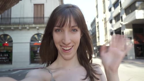 Smiling Woman Waving on City Street