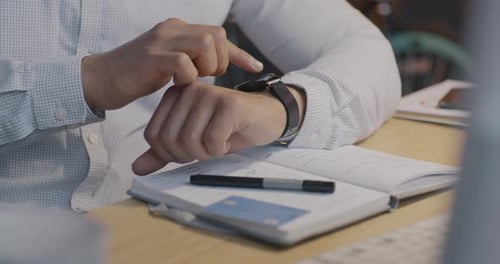 Closeup of Male Hand Using Smart Watch Touching Display at Desk in Dark Office at Night