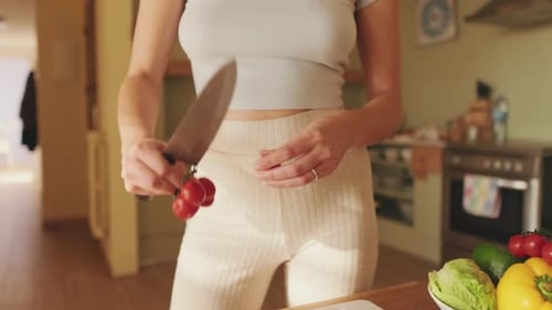 Close-up of young woman's hands cutting tomatoes making salad at home in the kitchen