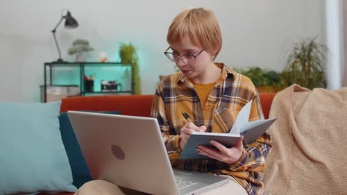 Young Adult Working on Laptop and Writing Notes
