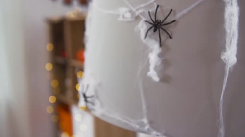 Halloween, Decoration And Holiday Concept - Lamp Decorated With Black Toy Spider On Artificial Co...