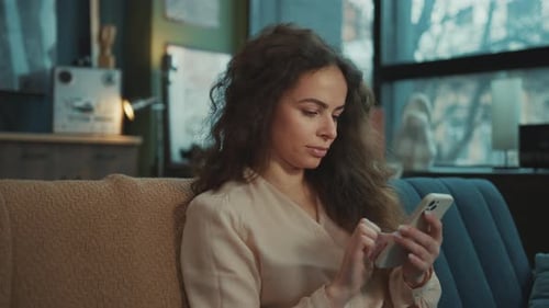 Relaxed Young Caucasian Woman Using Smartphone While Sitting on Couch in Loft Portrait of Smiling