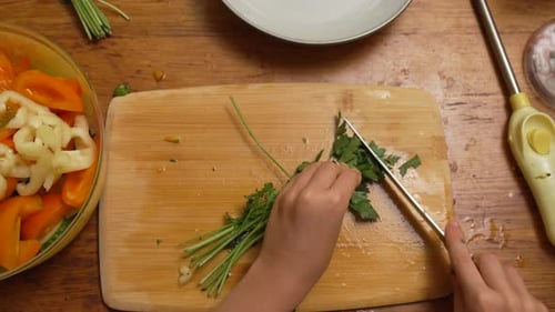 Hands chopping fresh parsley on cutting board