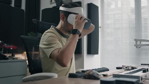 Person interacting with virtual reality glasses in a modern home studio, focused on creative tasks