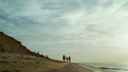Family silhouettes enjoying sunset walk on beautiful ocean beach coastline