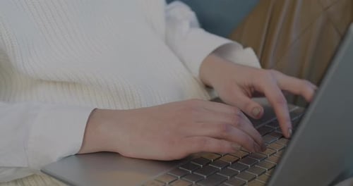 Nahaufnahme weiblicher Hände, die mit der Laptop-Tastatur tippen, während eine Frau den Computer benutzt