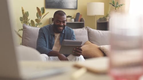 Black Man Video Chatting on Digital Tablet from Home