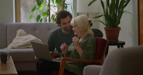 Brunette Guy Talks to His Mother and Helps Her Figure Out Her Laptop and Technology While Sitting