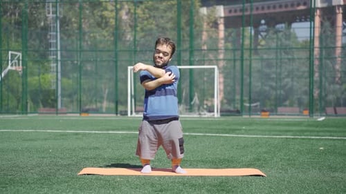 Man Doing Arm Stretches on Yoga Mat
