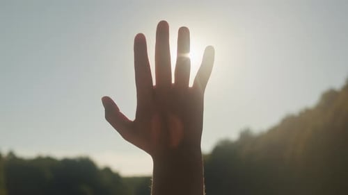 Hand einer jungen Frau bei Sonnenuntergang, Nahaufnahme, Sonne zwischen den Händen eines Touristenmädchens, Silhouette von Happy