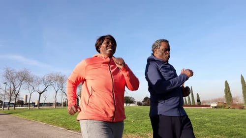 senior couple running in the park on a sunny day, couple of chubby people who do sports to take care