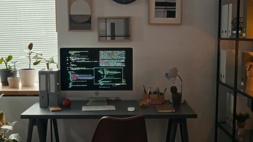 Aktenregal und Schreibtisch mit Computerbildschirm, auf dem Softwarecode im Büro angezeigt wird