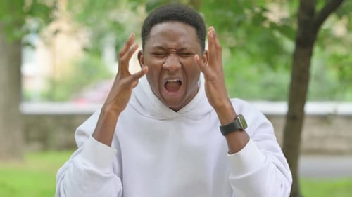 Young Man Shouts in Anger and Frustration Outdoors