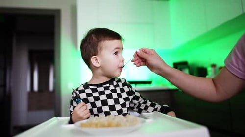 Garotinho jantando com a mãe. Nutrição para bebês famintos.