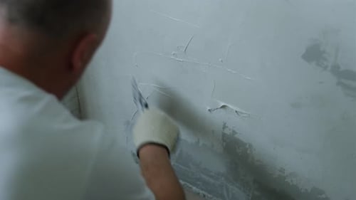 Man Applying Plaster to Wall During Home Renovation