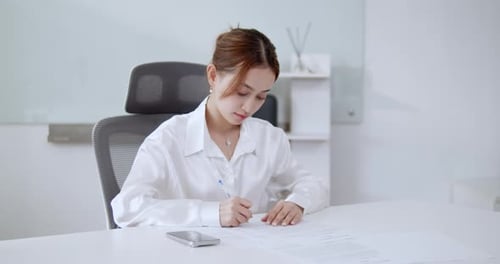 A focused woman interacts with her smartphone in a sleek office setting showcasing modern communicat