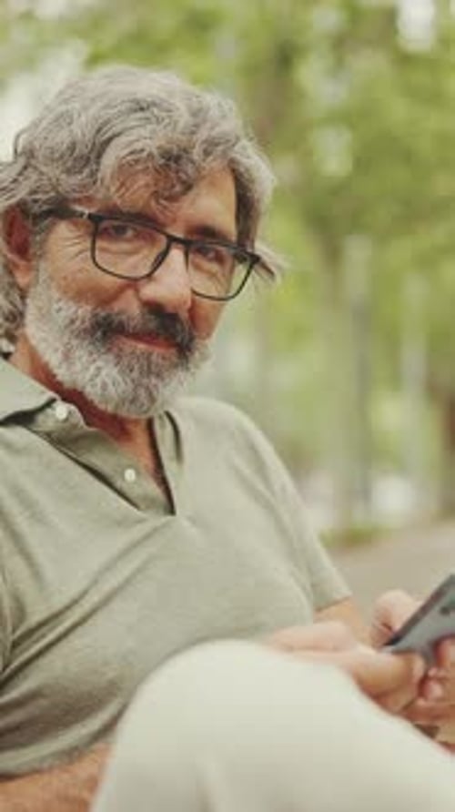 Man with Gray Hair Using a Smartphone Outside