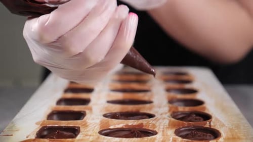 Chocolatier Pouring Melted Chocolate Into Molds in Pastry Shop Tempering Chocolate Craft Sweets