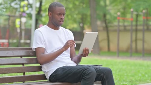 Man Surprised by Tablet News on Park Bench