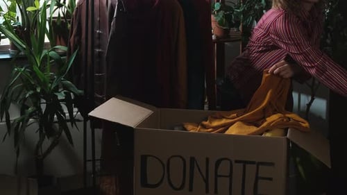 Young Woman Preparing Clothes for Donation