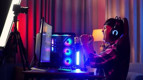 Side View Of Asian Boy Streamer Celebrating Winning Game On Personal Computer