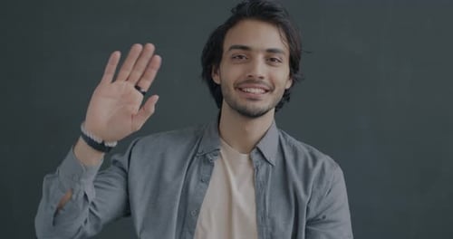 Smiling Man Waves Hello in Close Up Shot