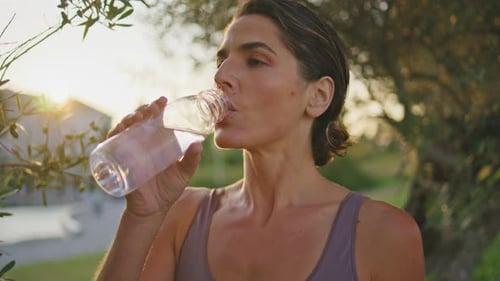 Athletic Lady Renewing Water Balance Intense Workout in Sunrise Park Closeup