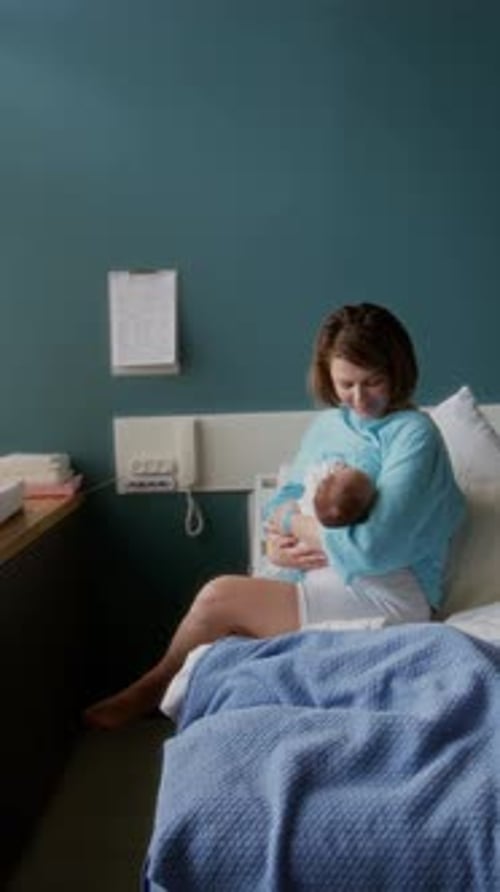 Mother Holding Newborn Baby in Hospital Bed