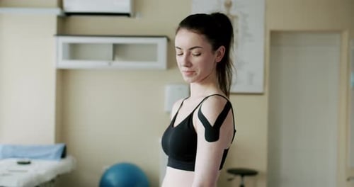 Woman with Medical Tape on Shoulder in Clinic