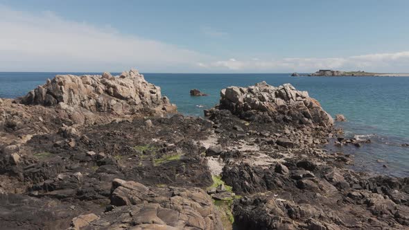 Drone flight at low tide over rocky foreshore with rockpools and birds ...
