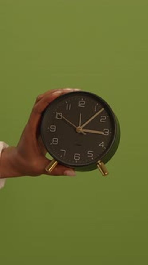 A Beautifully Designed Vintage Alarm Clock Displayed Against a Soothing Green Background