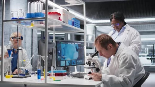 Equipe de funcionários estudando bandeja de amostra sob o microscópio para estudo de pesquisa