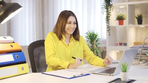 Young woman working in home office is surprised and looking at camera in amazement.