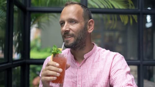 Happy, Young Man Drinking Cocktail Sitting in Cafe 30s