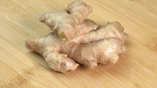 Fresh whole ginger root rotate on wooden background close up. Spices and herbs seasoning for cook